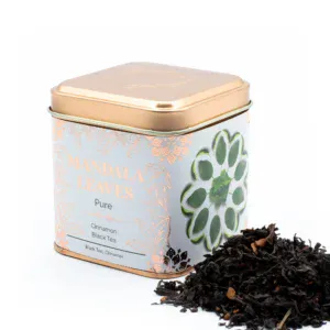 Square peach Mandala Leaves tea tin next to loose-leaf cinnamon black tea.