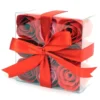 A transparent gift box with red and pink soap roses tied with a red satin ribbon.