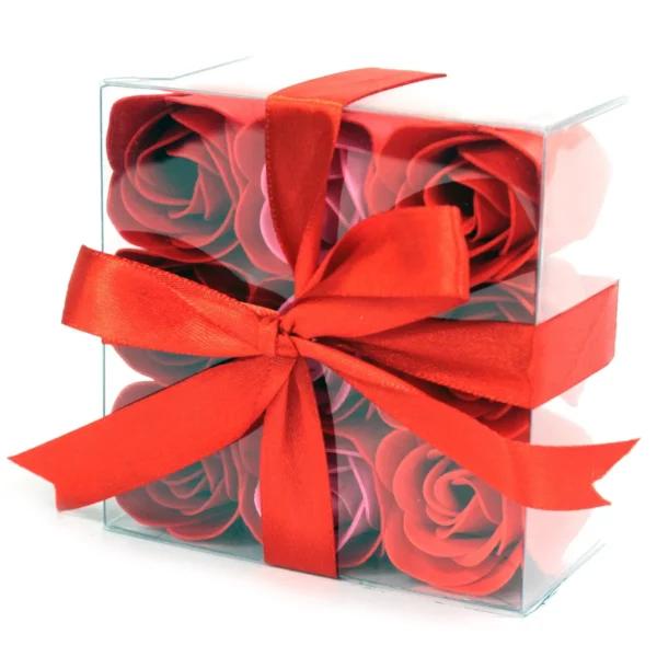 A transparent gift box with red and pink soap roses tied with a red satin ribbon.