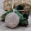 Silver wire Tree of Life pendant with rose quartz stone against a rough mineral background.
