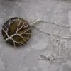 A silver wire-wrapped tiger’s eye stone pendant necklace on a fine silver chain.
