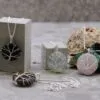 Wire-wrapped tree of life gemstone pendants displayed on concrete blocks and natural stones.