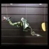 A colourful dragon marionette with green wings and blue head suspended by strings against a dark background.