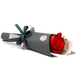 A single red rose wrapped in dark grey paper with a green and lavender ribbon bow.