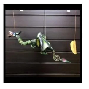Green Metallic Marionette Dragon Puppet - Curled Tail Design A green metallic marionette dragon puppet with curled tail suspended by strings against a dark background.