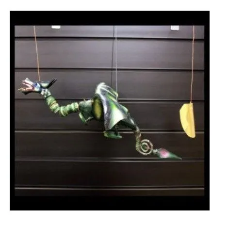 A green metallic marionette dragon puppet with curled tail suspended by strings against a dark background.