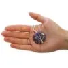 A hand holding a purple gemstone pendant wrapped in silver wire shaped like a tree.