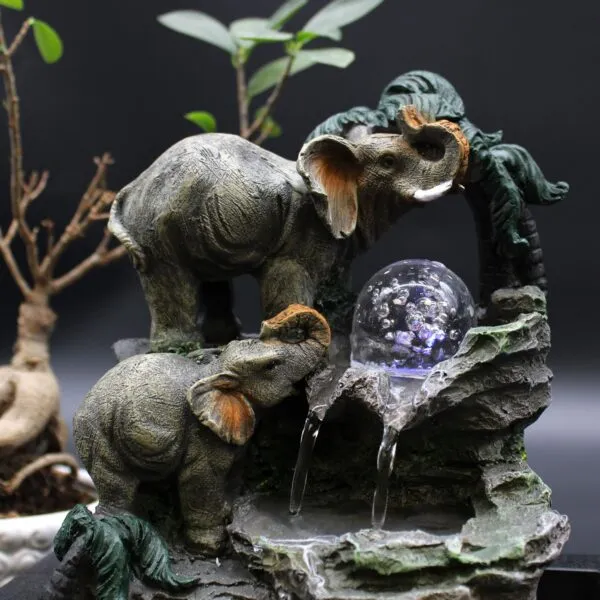Elephant Tabletop Fountain Resin Grey - Crystal Ball Waterfall Two sculpted elephants with a crystal ball tabletop fountain surrounded by greenery and gentle flowing water.