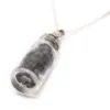 A small glass vial pendant necklace filled with dark natural stones on a silver chain.