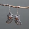 bG9jYWw6Ly9tZWRpYS8xUS9KQy82MFIzMEMxRzZNVEtKQzFRLzI2Y2E3NmQ3LmpwZWc.webp Silver and Gold Earring - Angel Wings