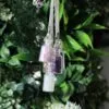 Three small glass bottle pendants with rose quartz, amethyst, and moonstone crystals on silver chains.