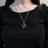 A silver tree of life pendant on a fine chain worn over a black long-sleeved shirt.