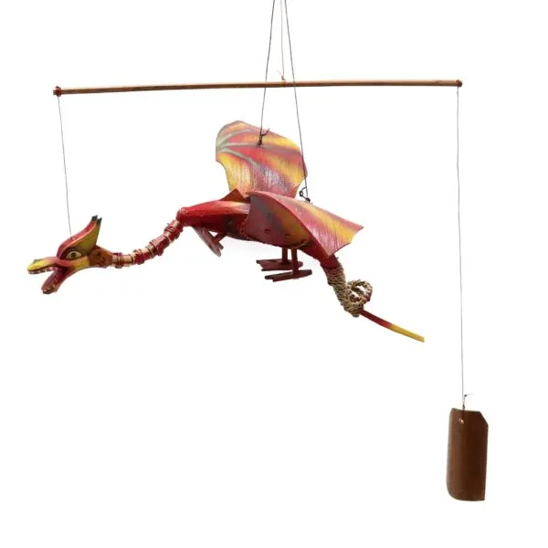 A handcrafted red and gold dragon mobile hanging from a wooden rod with a balancing counterweight.