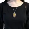 A silver wire-wrapped tiger’s eye pendant on a delicate chain worn over a black shirt.