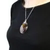 Silver wire-wrapped brown gemstone pendant necklace worn over a plain black top.