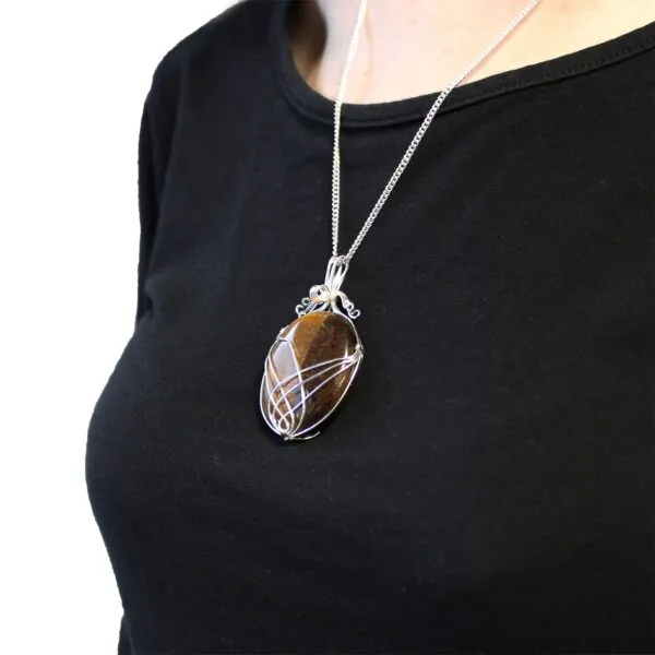 Silver wire-wrapped brown gemstone pendant necklace worn over a plain black top.
