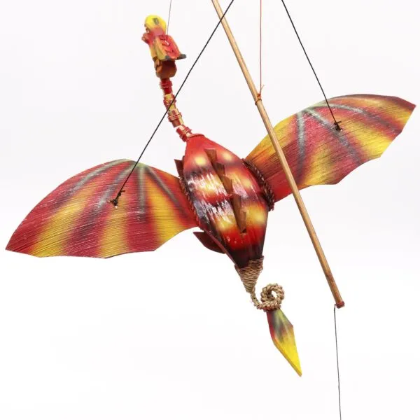 A colourful handmade bird-like hanging puppet with red, yellow, and orange painted wooden wings.
