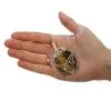 A silver wire-wrapped tiger’s eye gemstone pendant resting on an open adult hand.
