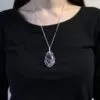 Silver wire-wrapped amethyst pendant necklace on a person wearing a plain black round-neck top.