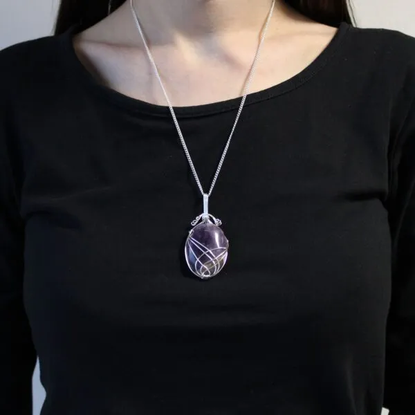 Silver wire-wrapped amethyst pendant necklace on a person wearing a plain black round-neck top.