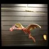 A red and gold dragon marionette suspended on strings against a dark black panel background.