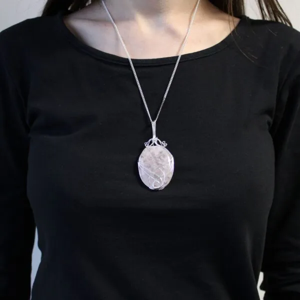 Rose Quartz Pendant Necklace Silver Wire Wrapped Design A silver wire-wrapped rose quartz pendant necklace worn over a plain black top.