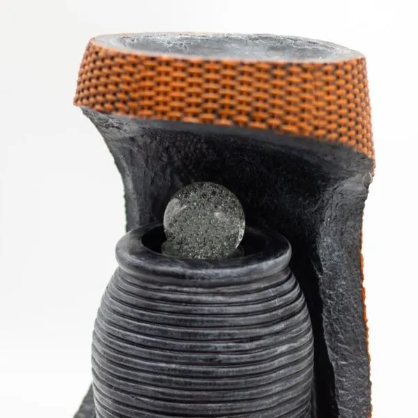 Modern black resin tabletop fountain with clear glass sphere and orange woven accent band.