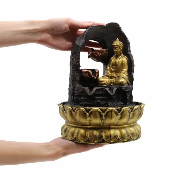 Golden Buddha Tabletop Fountain Resin Sculpture - Lotus Base A small golden Buddha tabletop water fountain with copper bowls held gently in two hands.