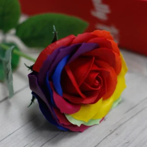 Rainbow Soap Rose Flower - Multicolour Velvet Petals Vibrant multicolour rainbow soap rose with lifelike velvet petals on a light wooden surface.