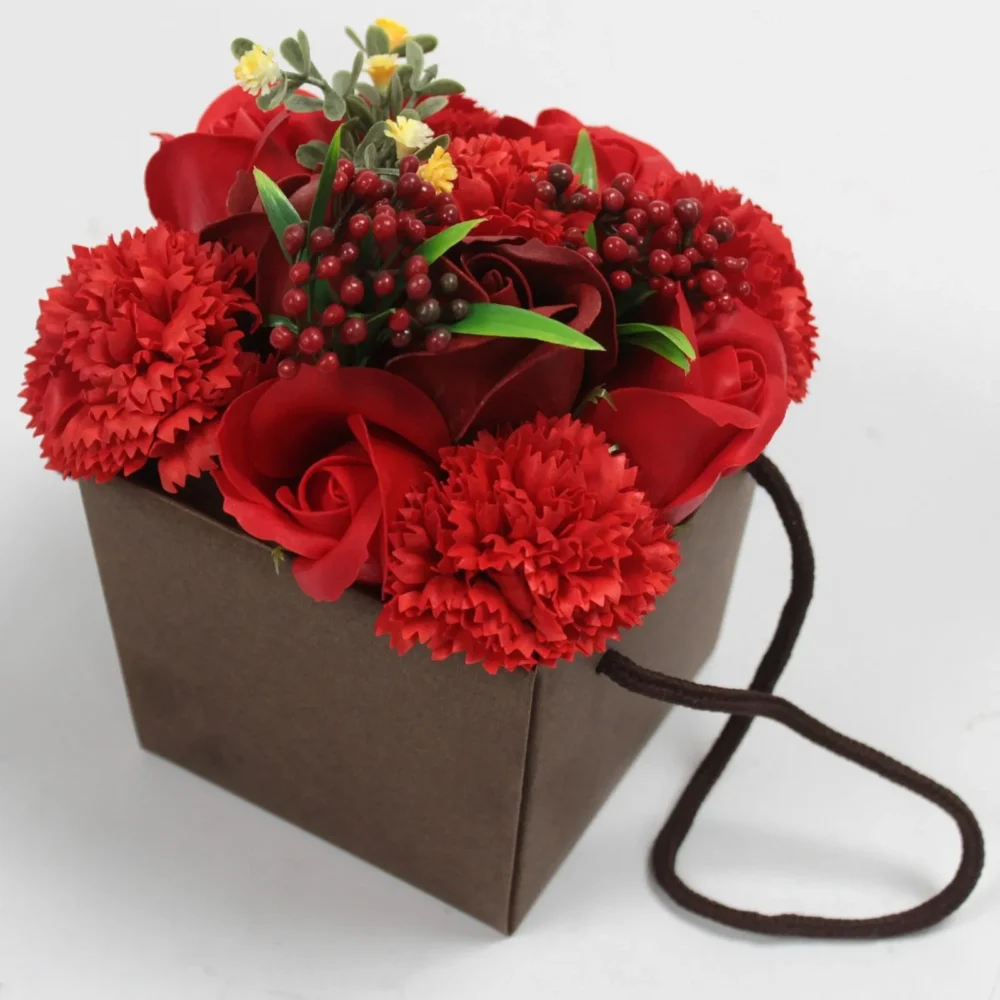 A red rose and carnation bouquet arranged in a brown square gift box with handle.