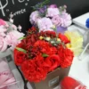 Red Rose And Carnation Bouquet Gift Box - Vibrant Floral Display A red rose and carnation bouquet in a brown gift box surrounded by pastel floral arrangements.
