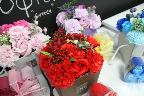 Red Rose And Carnation Bouquet Gift Box - Vibrant Floral Display A red rose and carnation bouquet in a brown gift box surrounded by pastel floral arrangements.