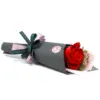 Red soap rose bouquet in a black paper cone tied with printed ribbon.