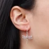 Expressive Accessories Close-up of a silver dragonfly filigree earring with rose gold accent on an ear.