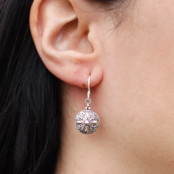 Close-up of a silver filigree floral dangle earring with intricate mixed-metal detailing.