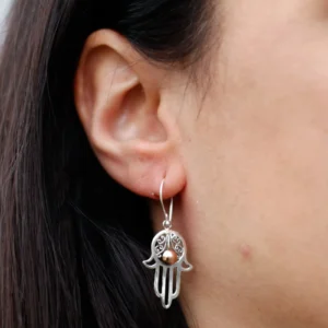 Close-up of a woman wearing a sterling silver Hamsa hand earring with copper accent.