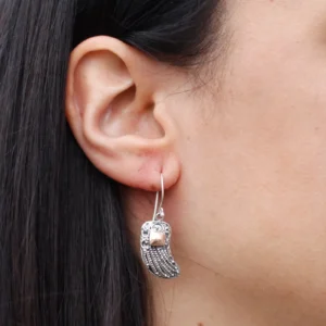 Close-up of a silver feather drop earring with a rose gold cube accent.