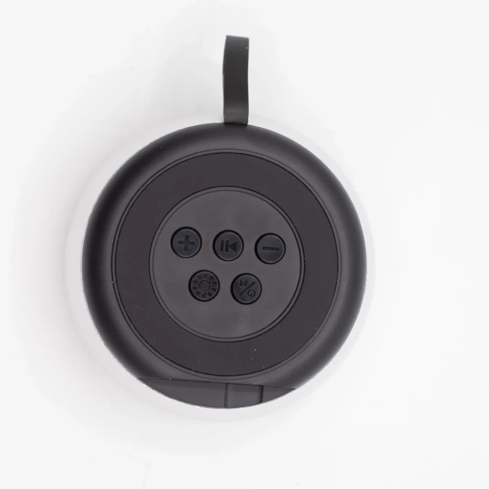 A black and white round Bluetooth shower speaker with control buttons and a hanging strap.