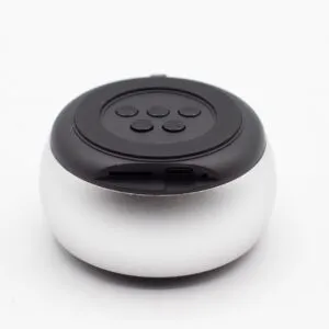 A small round silver and black Bluetooth speaker with top control buttons and charging port.