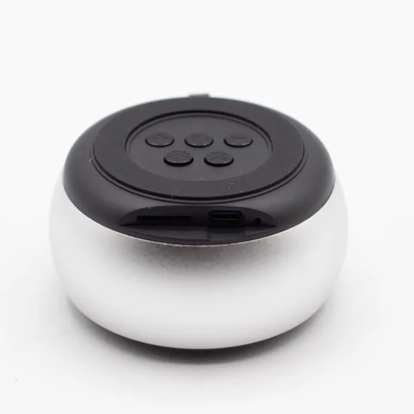 A small round silver and black Bluetooth speaker with top control buttons and charging port.