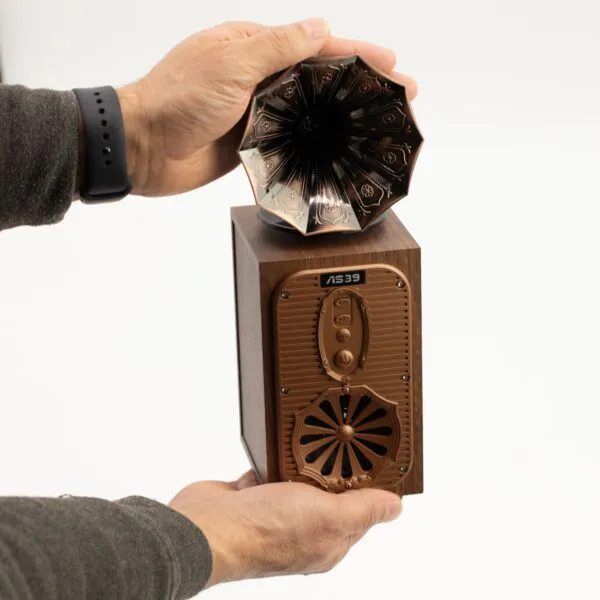 Vintage Wooden Gramophone Speaker With Bronze Metal Horn Hands holding a small wooden vintage-style gramophone speaker with a decorative metal horn.