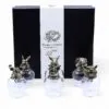 A black gift box set with five clear glasses topped by ornate bronze animal head lids.