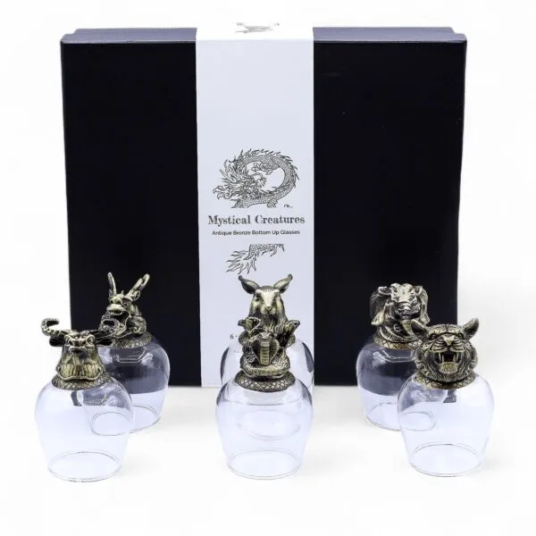 A black gift box set with five clear glasses topped by ornate bronze animal head lids.