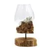Hand-blown glass bowl resting on natural driftwood base with rustic wooden stand for home décor.