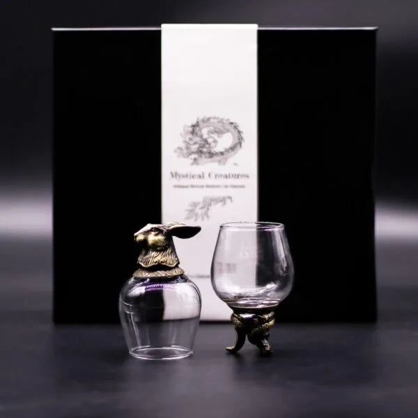 Two ornate glass goblets with bronze animal bases displayed before a black “Mystical Creatures” box.