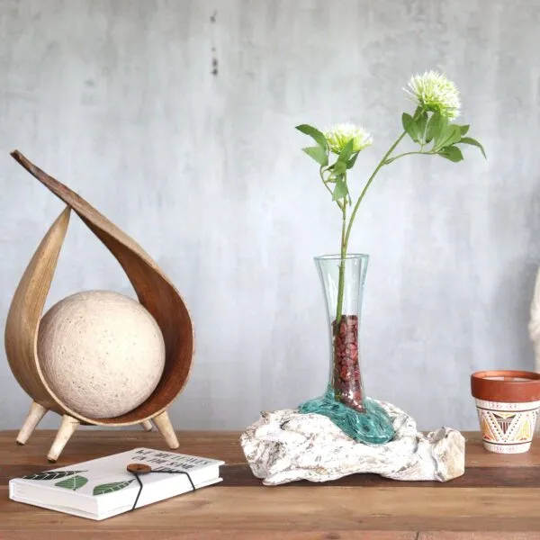 Minimalist wooden table with glass vase, green flowers, notebook, and natural decorative accents.