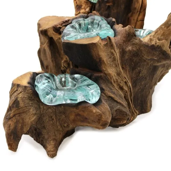 Molten glass sculpted onto natural driftwood base forming an organic aqua-blue decorative art piece.