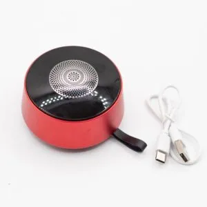 A small red portable Bluetooth speaker with a black top and coiled white USB-C charging cable.