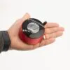 A hand holding a small red and black portable speaker against a plain white background.