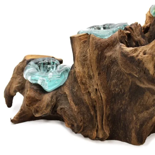 A decorative driftwood and turquoise glass sculpture blending natural wood textures with smooth molten glass.